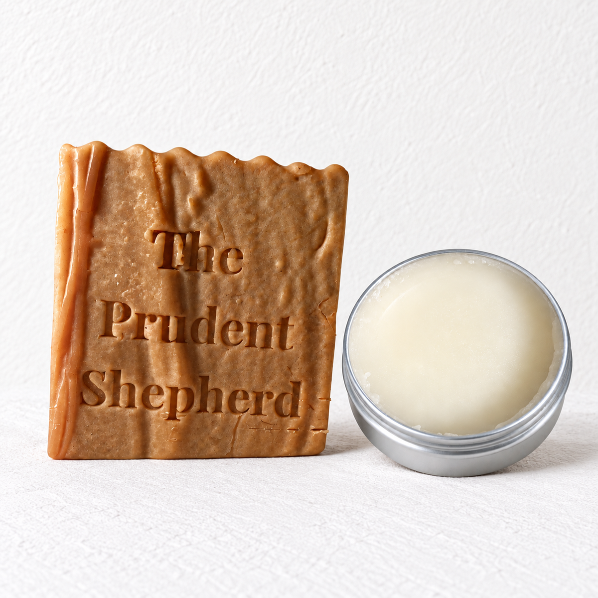 The Prudent Shepherd fragrance-free soap bar next to open 2 oz barrier balm.